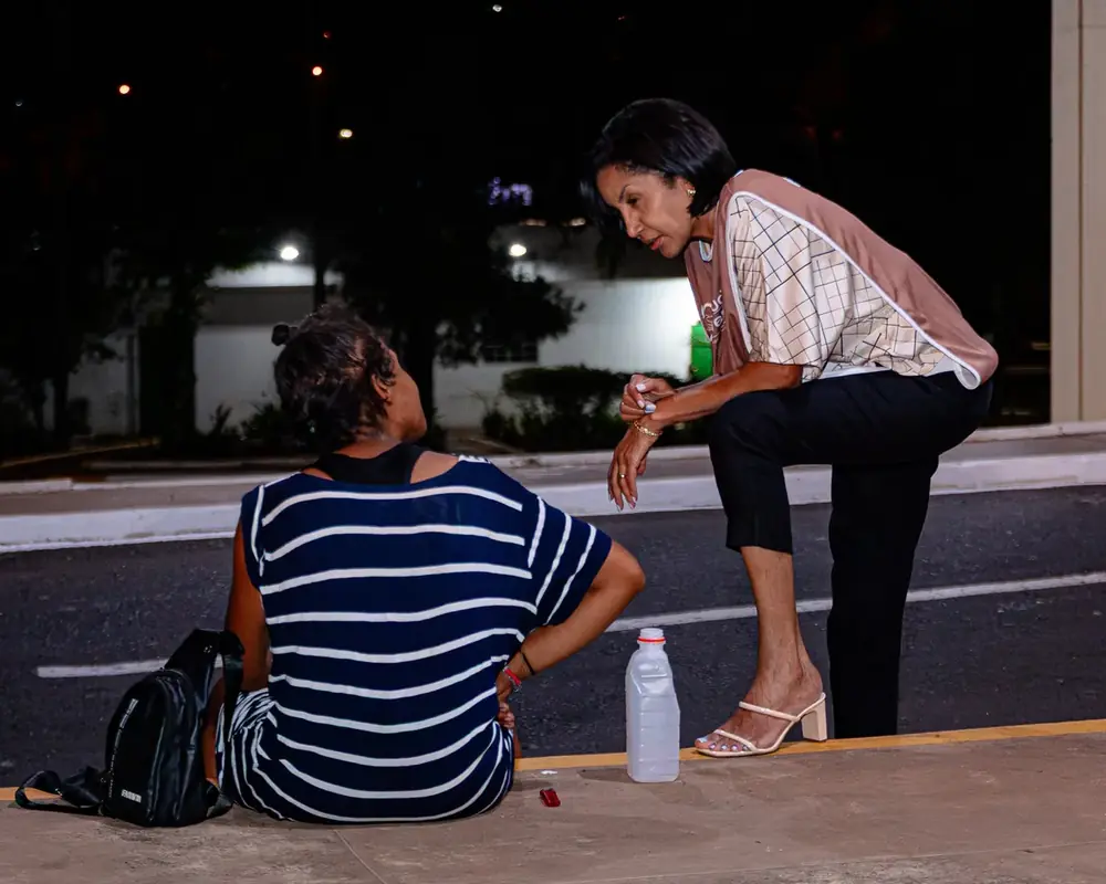 Lúcia Rosim atendendo pessoa em situação de rua, à noite