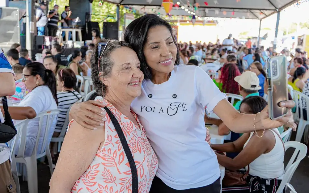 Lúcia Rosim abraçada com pessoas da comunidade
